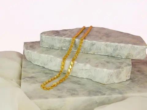 A gold rope chain draped over pale green marble slabs