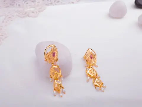 Gold drop earrings with small stones and pearls on white marble