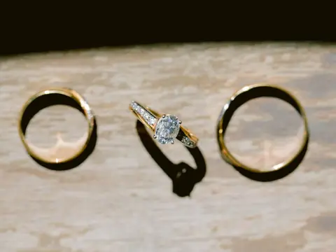 Two gold wedding bands and a diamond solitaire ring on pale marble