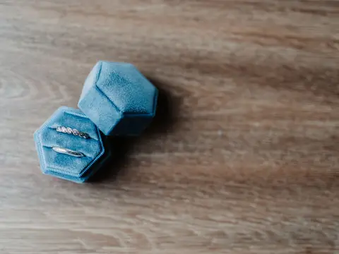 Two rings in an open blue velvet ring box on a wooden table