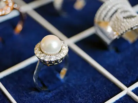 A pearl ring with a diamond halo in a jeweler's blue velvet tray