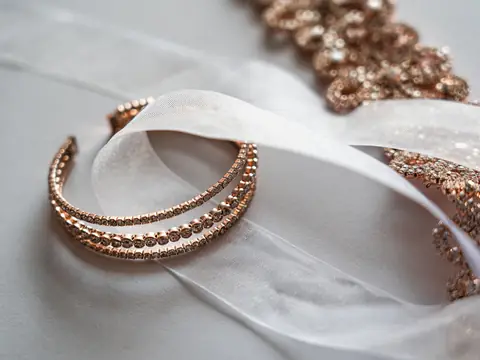 A rose gold beaded cuff bracelet on sheer white ribbon