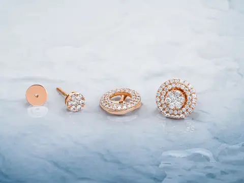 Rose gold earrings set with diamonds on pale blue marble
